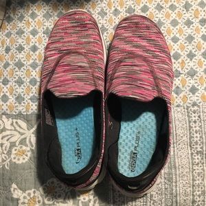 Pink and black sketchers go walk shoes.